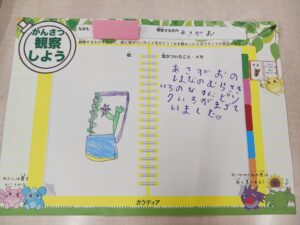 Colorful kids' observation workbook page with a hand-drawn plant, yellow binding, and playful characters along the bottom edge.