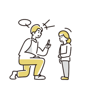 A man kneels and speaks to a standing girl, gesturing with his index finger as they talk to each other.
