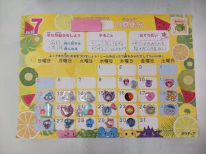 Colorful July calendar page for kids with sticker icons in date squares and fruit motifs on a yellow background.